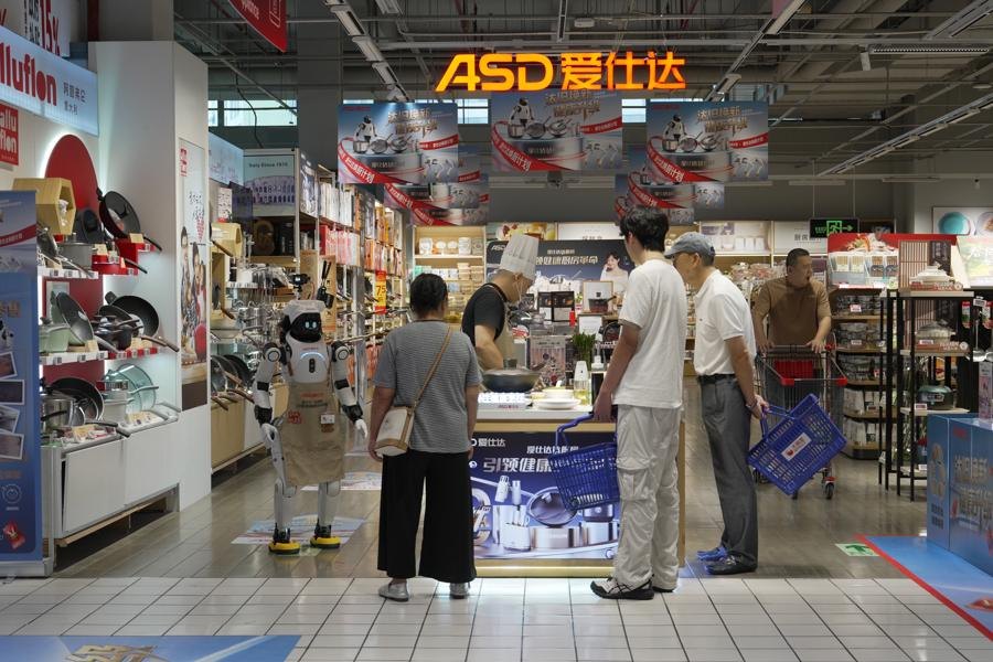 爱仕达门店里，戴着厨师帽和围裙的智元灵犀 X2 机器人「爱宝」正在为顾客导购