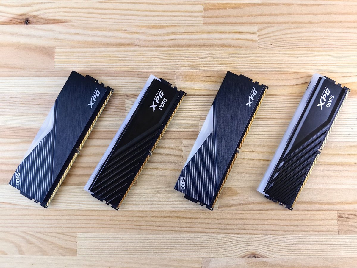 四条 DDR5 内存条并排平放在木纹桌面上